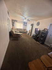 Living room with ceiling fan, a textured ceiling, and carpet