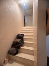 Stairs featuring a textured ceiling