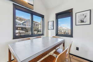 Dining room with light hardwood / wood-style floors and lofted ceiling