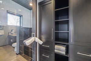 Bathroom featuring toilet, tile patterned flooring, and tile walls