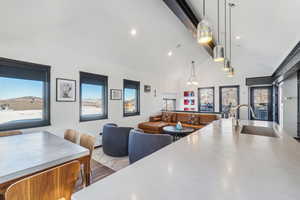 Kitchen with sink, hanging light fixtures, high vaulted ceiling, light hardwood / wood-style flooring, and beam ceiling