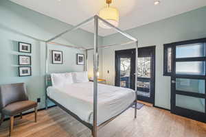 Bedroom featuring access to exterior, wood-type flooring, and french doors