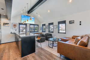 Living room with high vaulted ceiling, sink, wood-type flooring, and beam ceiling