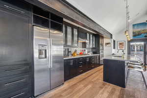 Kitchen featuring appliances with stainless steel finishes, hanging light fixtures, sink, an island with sink, and a breakfast bar area