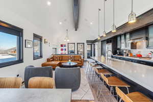 Interior space featuring pendant lighting, sink, backsplash, ventilation hood, and a breakfast bar area