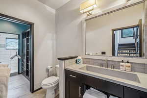 Bathroom with tile patterned floors, backsplash, toilet, and vanity