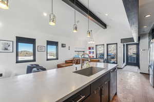 Kitchen featuring decorative light fixtures, sink, lofted ceiling with beams, and light wood-type flooring