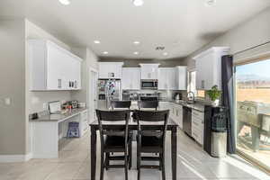 Kitchen featuring appliances with stainless steel finishes, sink, white cabinetry, light tile patterned floors, and a kitchen island