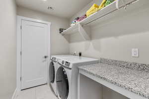 Washroom featuring light tile patterned floors and separate washer and dryer