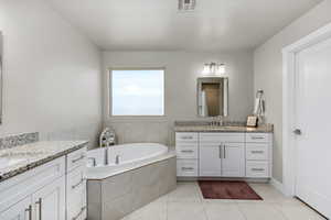 Bathroom with tiled bath, tile patterned floors, and vanity