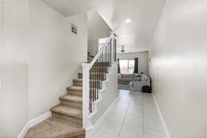 Stairway with ceiling fan, a textured ceiling, and tile patterned floors