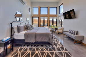 Bedroom featuring an AC wall unit, french doors, a towering ceiling, and concrete flooring