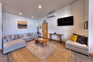 Living room featuring a wall mounted air conditioner and lofted ceiling