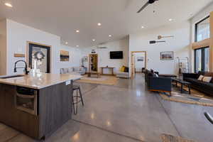 Kitchen with stainless steel oven, lofted ceiling, a center island with sink, sink, and dark brown cabinetry