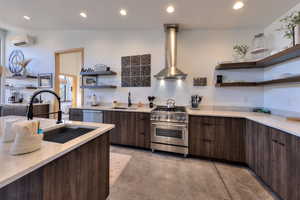 Kitchen with a wall mounted air conditioner, wall chimney exhaust hood, sink, and appliances with stainless steel finishes