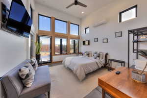 Bedroom with ceiling fan, a towering ceiling, and a wall unit AC