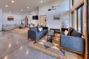 Living room with a towering ceiling and a wall mounted air conditioner