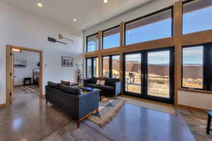 Living room with concrete flooring, french doors, and a towering ceiling