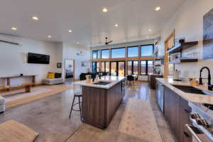 Kitchen with dark brown cabinetry, a kitchen island with sink, sink, an AC wall unit, and range