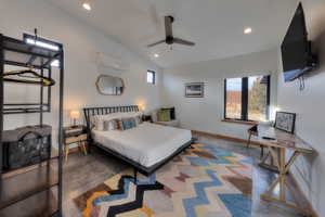 Bedroom featuring ceiling fan, an AC wall unit, multiple windows, and vaulted ceiling