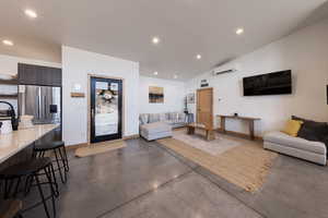 Living room with a wall unit AC and lofted ceiling