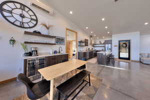 Dining room with an AC wall unit, sink, wine cooler, and vaulted ceiling