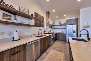 Kitchen featuring island exhaust hood, sink, light stone countertops, and stainless steel appliances