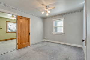 Carpeted spare room with ceiling fan and plenty of natural light