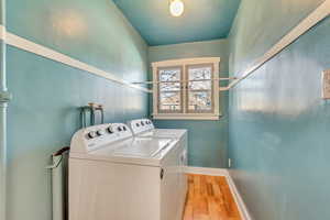 Laundry area featuring washing machine and clothes dryer and light hardwood / wood-style flooring