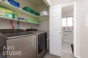 Laundry room with washing machine and dryer and light tile patterned flooring