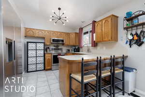 Kitchen featuring appliances with stainless steel finishes, lofted ceiling, sink, a kitchen breakfast bar, and kitchen peninsula