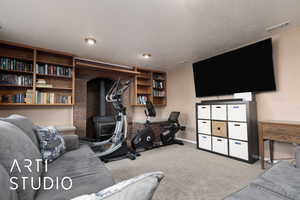 Exercise room featuring light carpet, a textured ceiling, and a wood stove