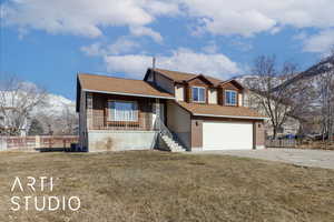 View of front facade featuring a garage, covered porch, a front yard, and a mountain view