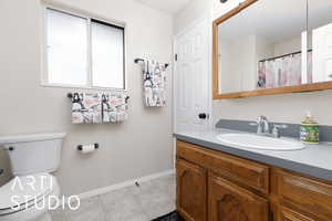 Bathroom with toilet, vanity, and tile patterned flooring