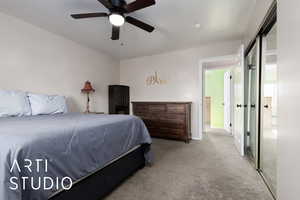 Carpeted bedroom with ceiling fan and a closet