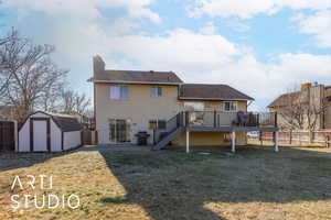 Rear view of house with a lawn, a wooden deck, and a shed