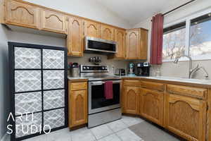 Kitchen with sink, light tile patterned flooring, lofted ceiling, and stainless steel appliances