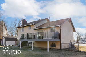 Rear view of house featuring a storage unit, cooling unit, a lawn, and a wooden deck