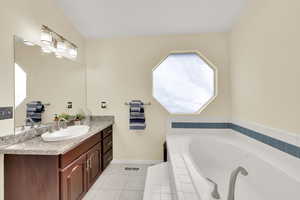 Bathroom featuring vanity, tile patterned floors, and tiled bath