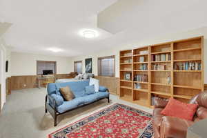 Living room featuring carpet floors, wooden walls, and a textured ceiling