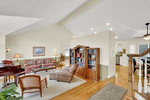 Living room with light hardwood / wood-style floors, lofted ceiling with beams, and ceiling fan