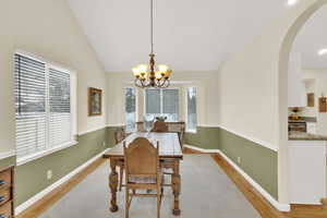 Dining room with an inviting chandelier, light hardwood / wood-style flooring, and vaulted ceiling