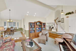 Living room featuring light hardwood / wood-style flooring, an inviting chandelier, and lofted ceiling with beams