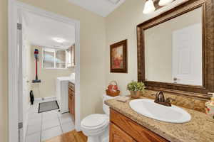 Bathroom with toilet, washing machine and dryer, tile patterned flooring, and vanity