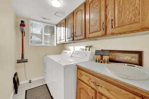 Laundry area featuring light tile patterned flooring, a textured ceiling, and washing machine and clothes dryer