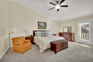 Carpeted bedroom with access to exterior, vaulted ceiling, and ceiling fan