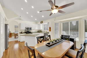 Dining area featuring sink, vaulted ceiling, ceiling fan, and light hardwood / wood-style flooring