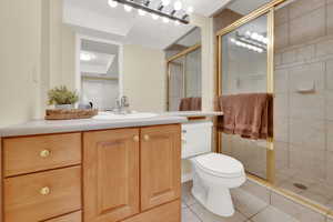 Bathroom featuring vanity, walk in shower, tile patterned floors, and toilet