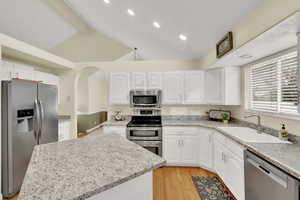 Kitchen featuring sink, white cabinetry, appliances with stainless steel finishes, and lofted ceiling with beams