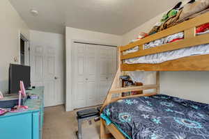 Carpeted bedroom with a closet and a textured ceiling